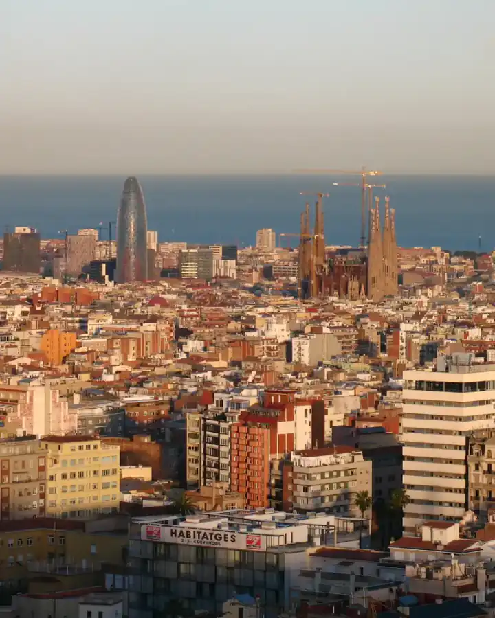 Barcelona al atardecer desde el parque del Putxet, con la Sagrada Família y la torre Glòries frente al mar